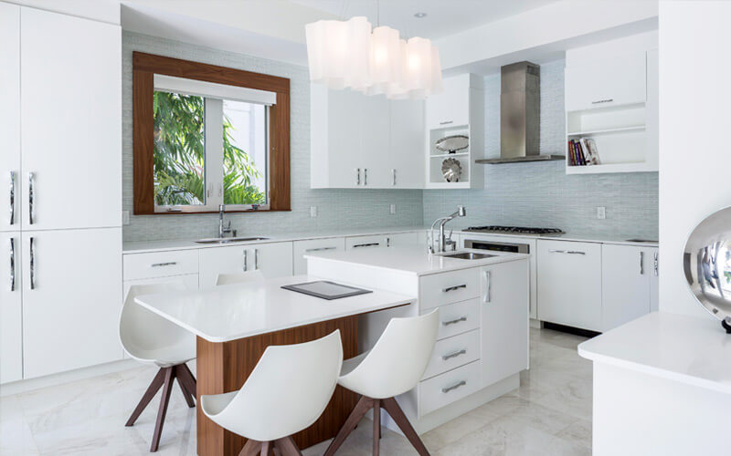 厨房配备了完全现代化的设施，包括光滑的白色橱柜和台面、微瓦蓝色后挡板、两部分式岛式橱柜、内置水槽和天然木质结构的较低用餐空间。