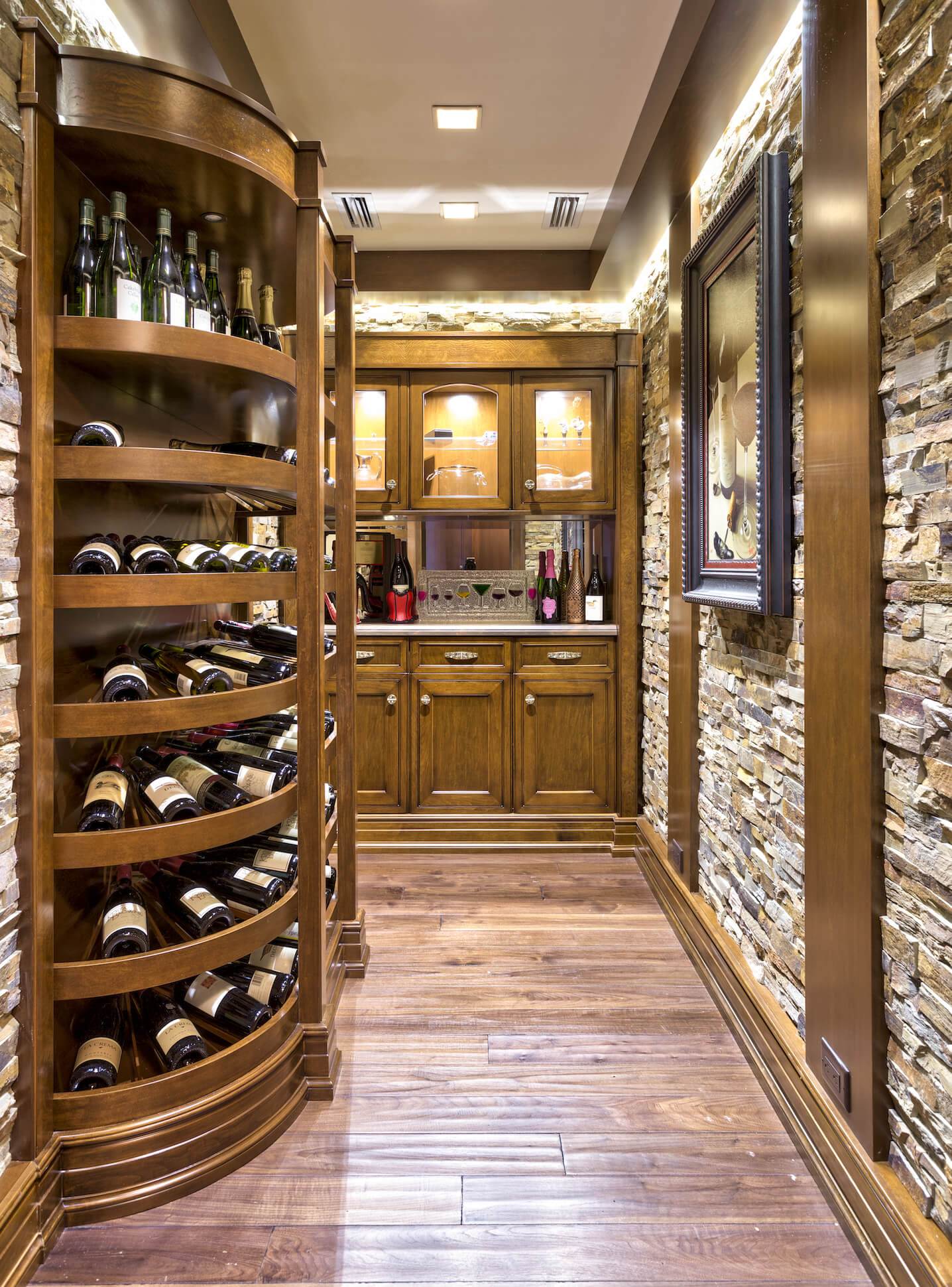 豪华的酒窖由石砖和丰富的木材混合装饰而成，右边是弯曲的架子，中间是小酒吧。内部照明的橱柜允许大胆展示玻璃器皿。