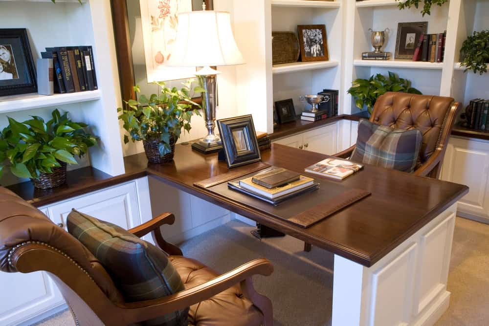 设计精美的家庭办公室，有白色和棕色的桌子，植物和架子。