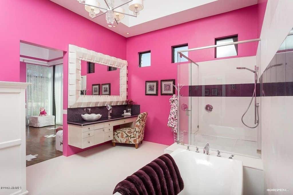 迷人的粉红色主浴室设有步入式淋浴和浴缸，以及带有容器水槽和花椅的漂浮梳妆台。