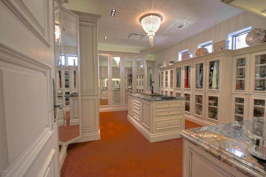 巨大的步入式衣橱，白色橱柜，包括玻璃面储物柜。