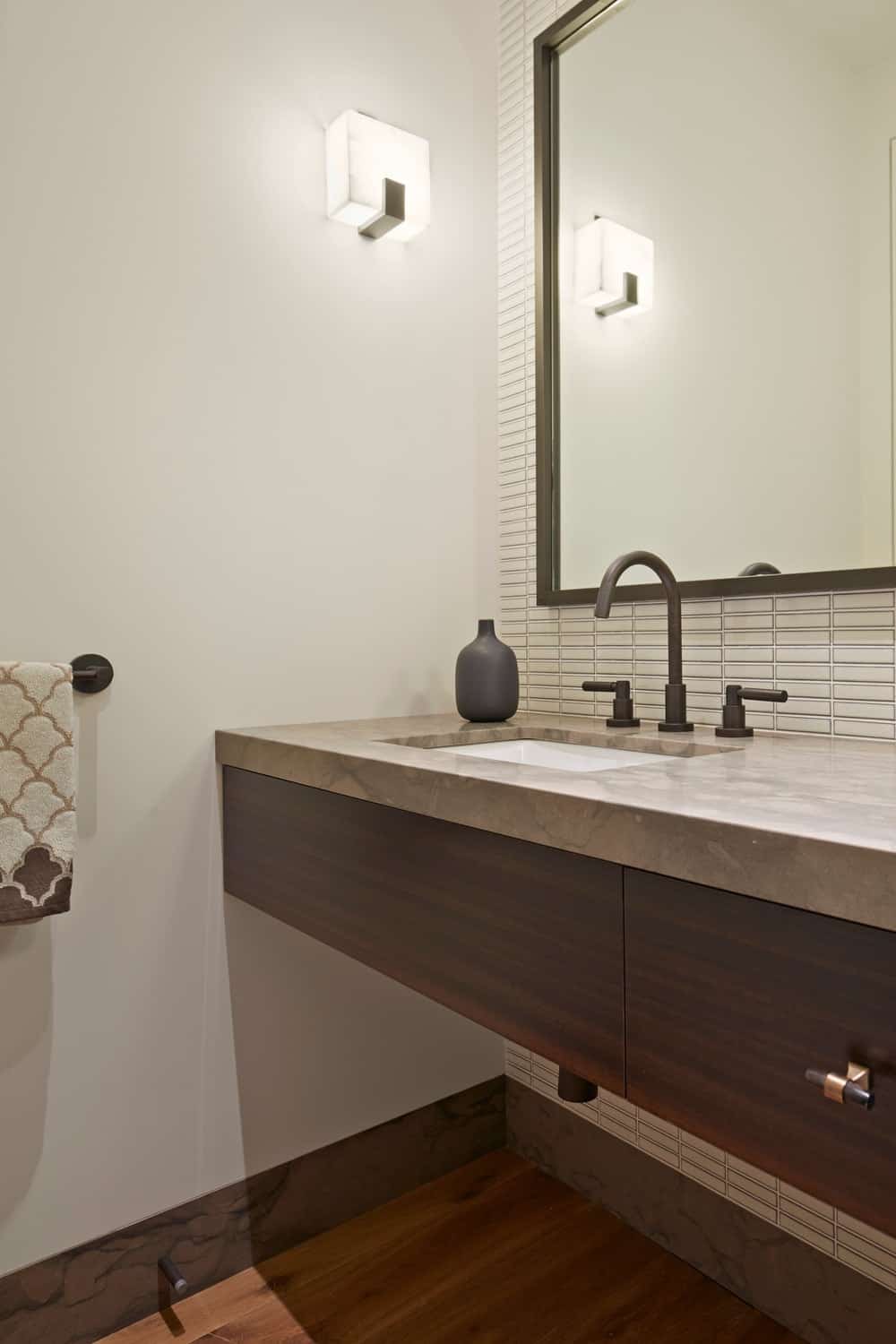 现代化的浴室，带有浮动的梳妆台和大理石台面，以及白色的墙壁和墙壁照明。图片来源:Bruce Damonte