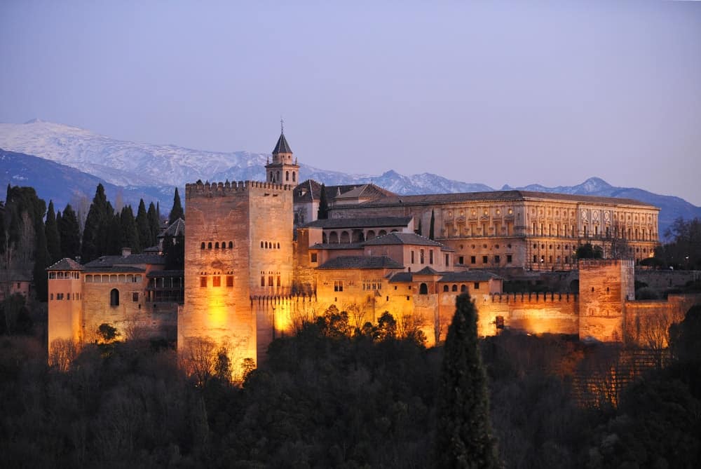 西班牙安达卢西亚的格拉纳达，阿尔罕布拉宫与科马雷斯塔、查理五世宫和内华达山脉在日落时的背景。