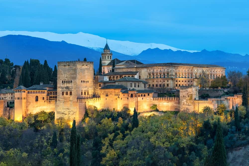 阿尔罕布拉宫，一座中世纪摩尔人的堡垒，被黄色的秋天树木包围，在西班牙安达卢西亚的格拉纳达的夜晚被照亮。