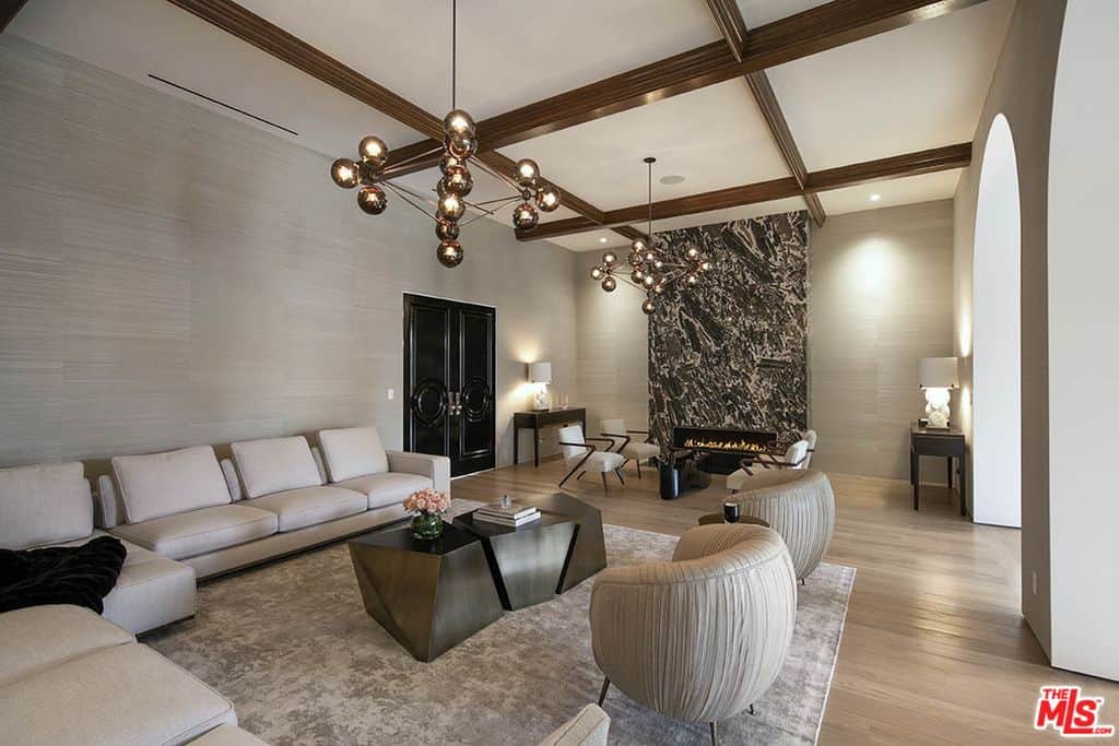 客厅有木格子天花板，轻木地板，拱形入口和巨大的浅米色组合沙发。看看那壮观的发光壁炉。