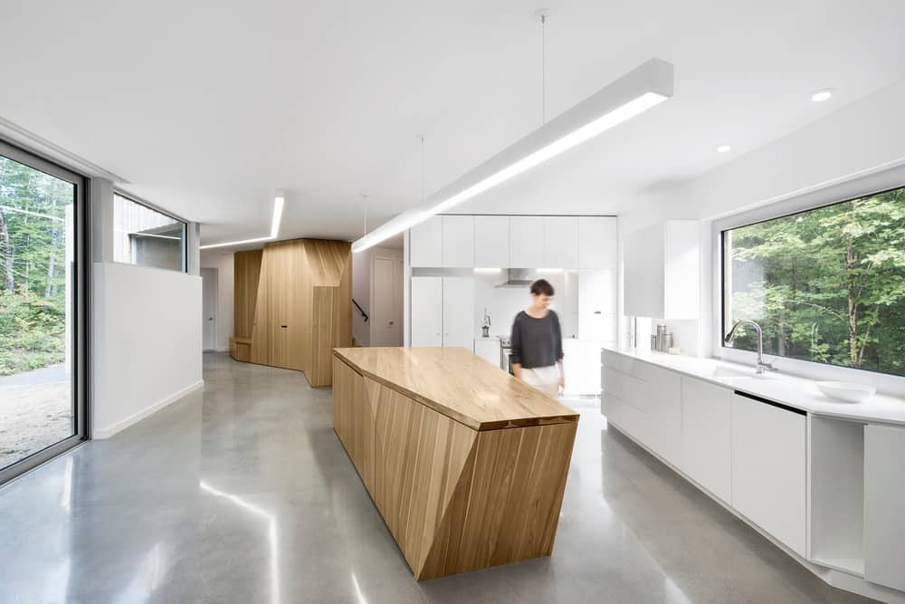 极简主义现代厨房与天然木材和白色橱柜在狭窄的房子