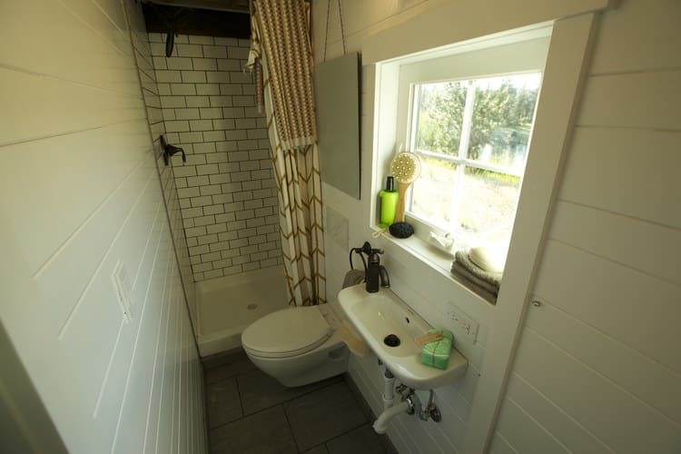 这是一个小房子里的一个相当大的浴室的照片，包括浮动水槽，厕所和淋浴。