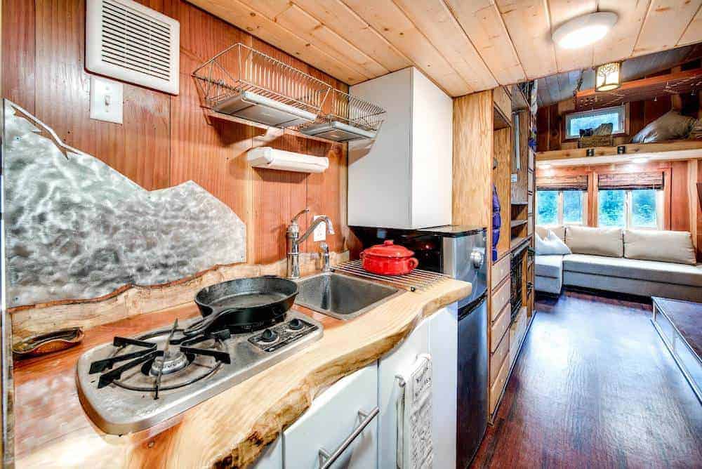 近距离照片的一个小家庭厨房定制的木制品，水槽，橱柜，后挡板和范围。