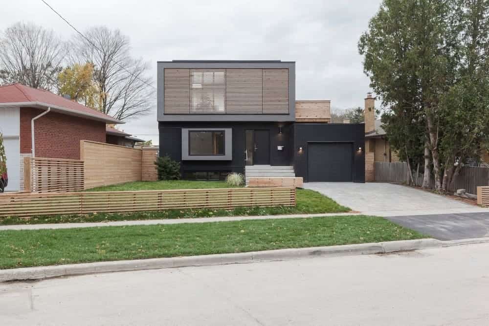 一栋黑色外观的现代住宅，一条带车库和草坪的车道。