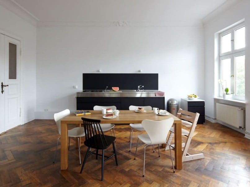宽敞的用餐室拥有时尚的人字形风格的硬木地板，周围环绕着白色墙壁和白色天花板。