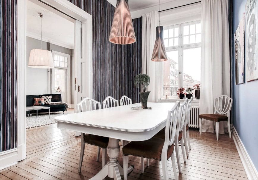 特写镜头看看这间餐厅的白色餐桌，坐落在硬木地板上面。它是由优雅的吊灯悬挂在高大的天花板上的照明。