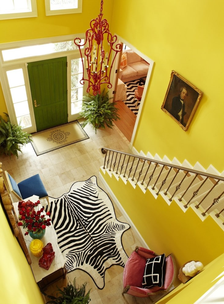鸟瞰图的黄色门厅提供了一个红色华丽的垂饰和斑马地毯，铺在米色瓷砖地板。它配备了舒适的椅子和大理石顶板桌，并配有雕刻木镜子。