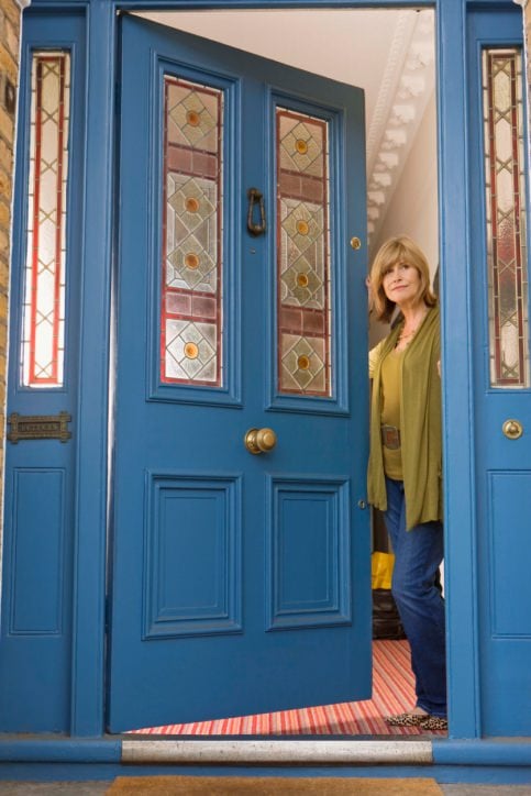 一扇漂亮的蓝色前门，装饰着几何图案排列的彩色玻璃板。它由一个黄铜旋钮和一个青铜门环完成。