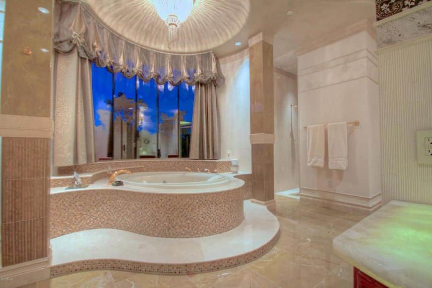 一个定制的主浴室拥有一个华丽的浴缸设置在一个令人惊叹的天花板下，由花式吊灯照明。浴室还设有一间步入式的角落淋浴间。