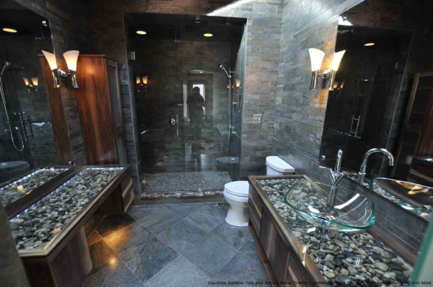一个现代化的主浴室，有瓷砖地板和墙壁，以及步入式淋浴间。有一个粉末桌和一个洗手台，都有时髦的台面。