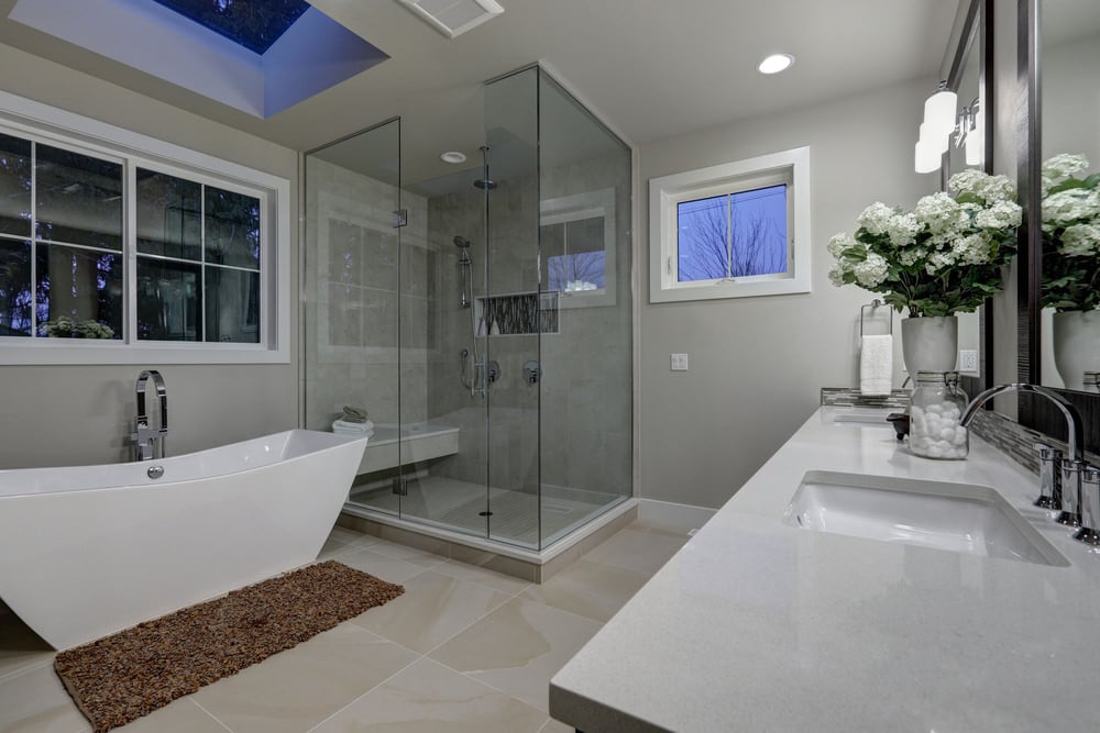 主浴室采用灰色墙壁和米色瓷砖地板，以及独立浴缸上方的天窗。有一个步入式淋浴和一个有两个水槽的水槽台。