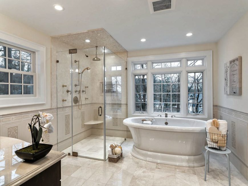 主浴室有经典的米色瓷砖地板和一个单一的水槽柜台。有一个深度浸泡的独立浴缸和一个玻璃步入式淋浴房。