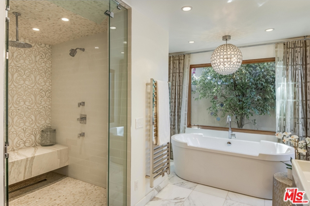 小型主卫生间，大理石瓷砖地板和普通天花板。窗户旁边有一个大型独立式深浴缸，旁边有一个步入式淋浴间。