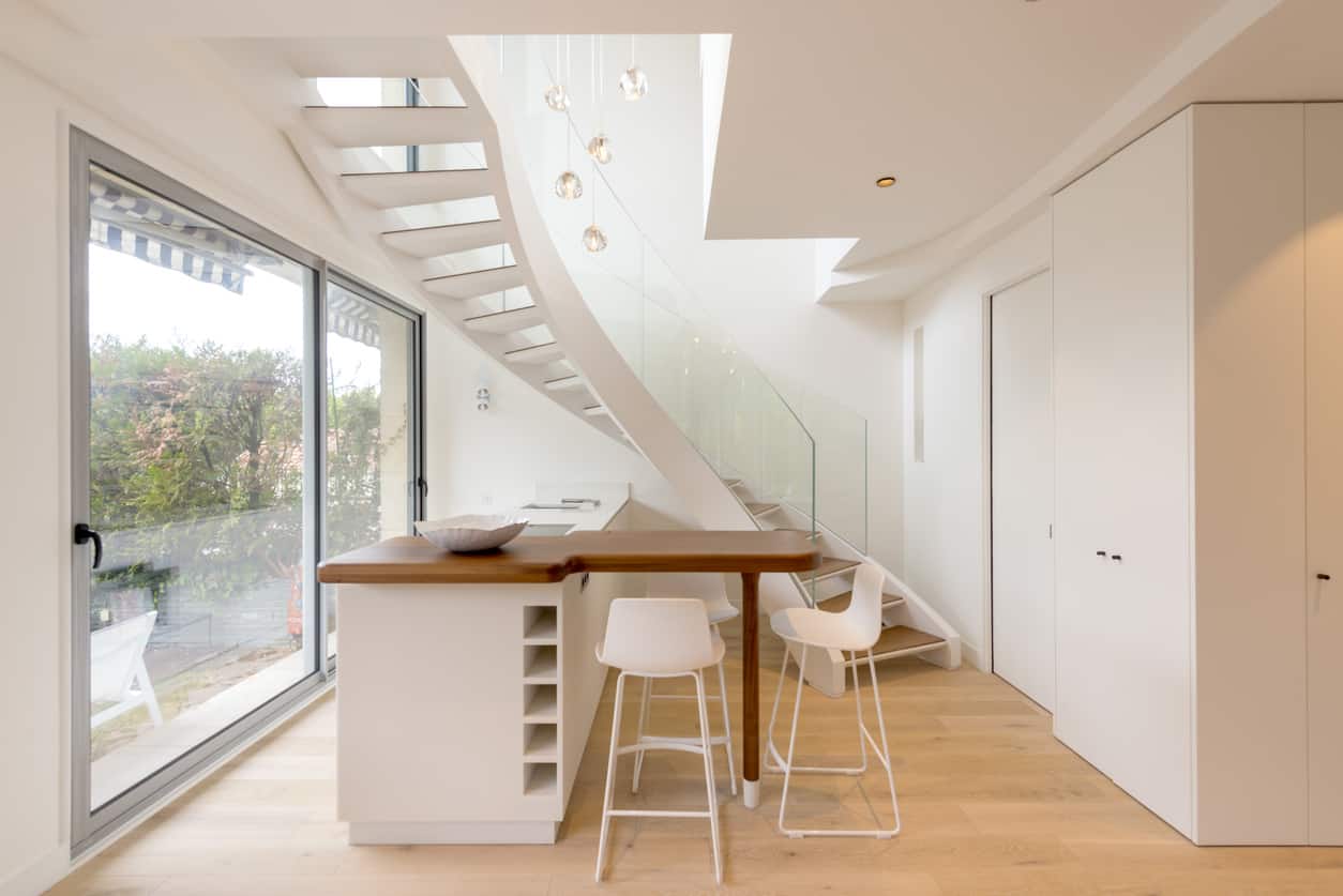 白色的小厨房靠近楼梯，面向玻璃滑动门。
