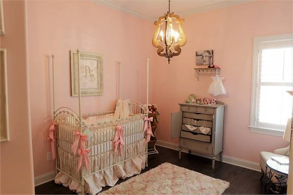育婴室,粉色的墙,黑暗的实木地板,有缘的摇篮,一个毛茸茸的地毯。