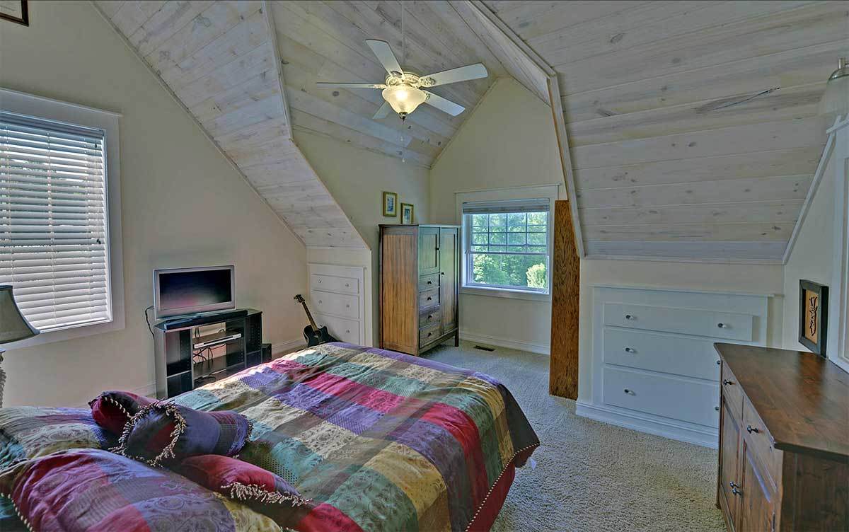 这间卧室有地毯地板，拱形天花板和木制家具。