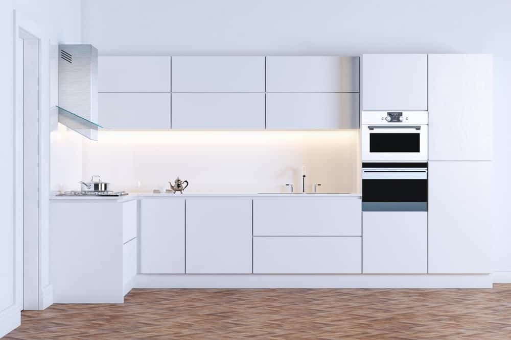 这是一个近距离观察与一致的白色色调简约的现代厨房的橱柜,柜台和石膏墙壁地板的补充。