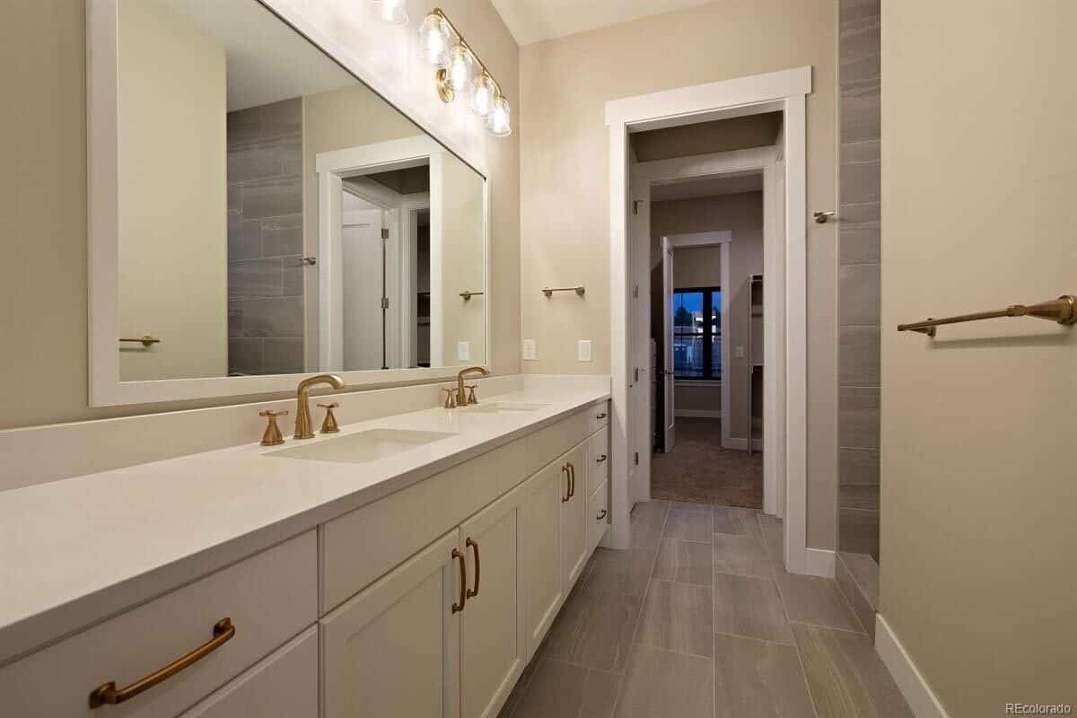 这间浴室设有一个带双水槽的长梳妆台和一面大镜框镜子。