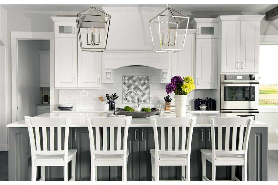 厨房用灰色和白色的橱柜,白色的地铁瓷砖连壁,早餐岛加上几笼吊坠。