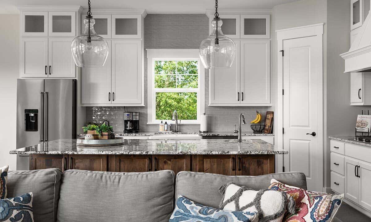 与白色的橱柜,厨房花岗岩台面,早餐岛上覆盖着玻璃吊坠。