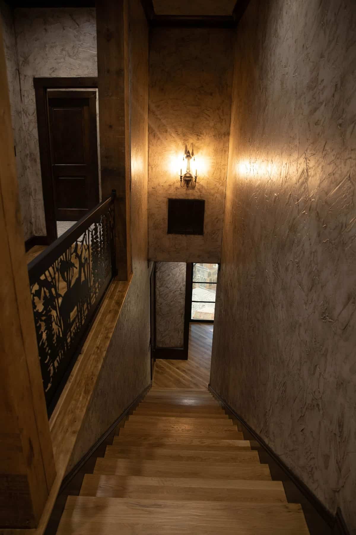 一个温暖的蜡烛烛台固定在有纹理的混凝土墙上，照亮了楼梯大厅。